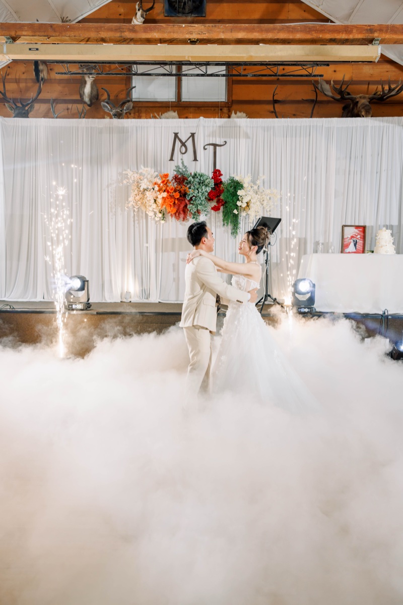 Vietnamese wedding reception first dance — bride and groom embracing in dry ice fog with sparkler fountains and floral arch backdrop, photographed by Kevin Socola Films in the DMV